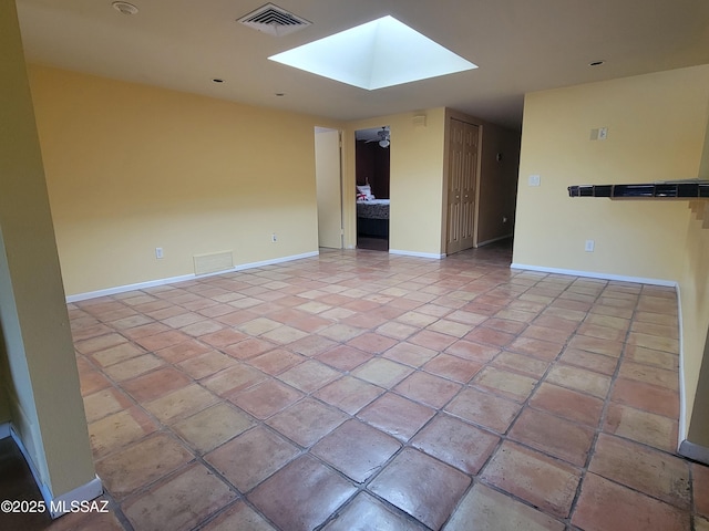 spare room featuring a skylight and light tile patterned floors