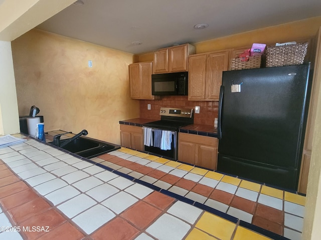 kitchen with sink, backsplash, black appliances, tile countertops, and light brown cabinets