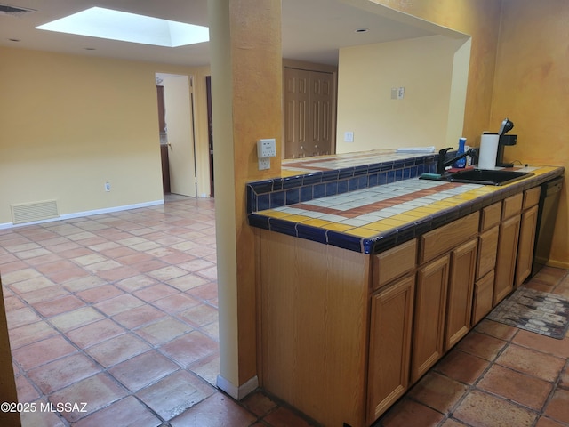 kitchen featuring sink, tile counters, and black dishwasher