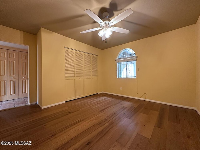 8034 E Shadow Ln, Tucson, AZ 85750 - unfurnished bedroom featuring dark wood-style flooring, baseboards, a closet, and a ceiling fan