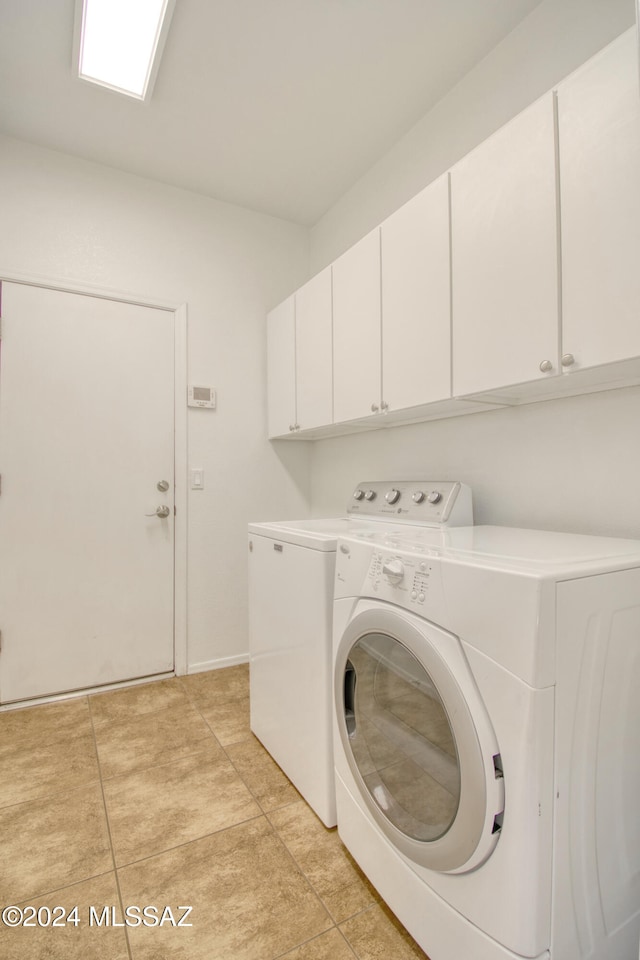 clothes washing area with washing machine and dryer, light tile patterned floors, and cabinets