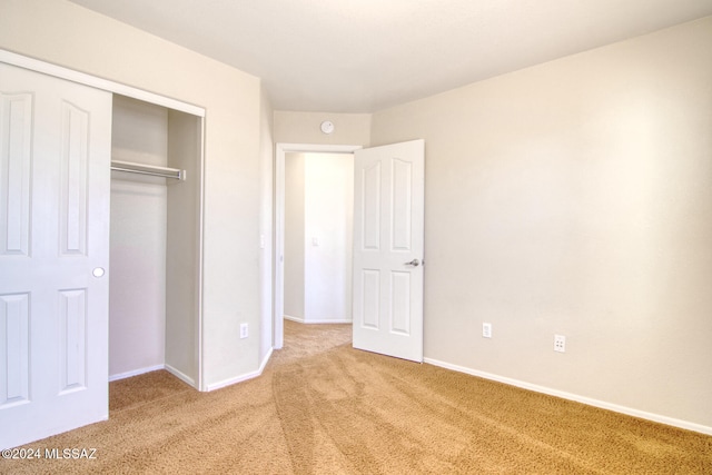 unfurnished bedroom featuring light carpet and a closet