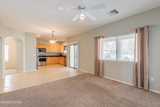 unfurnished living room featuring light colored carpet and a healthy amount of sunlight