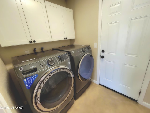 clothes washing area featuring washer and dryer and cabinets