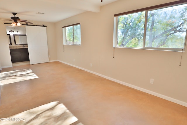 spare room featuring carpet flooring, a barn door, plenty of natural light, and ceiling fan