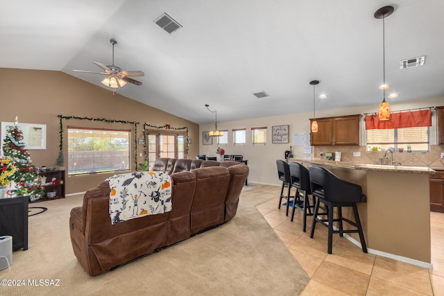 living room with ceiling fan, plenty of natural light, light tile patterned floors, and vaulted ceiling