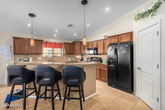 kitchen with black appliances, decorative light fixtures, a breakfast bar, and vaulted ceiling