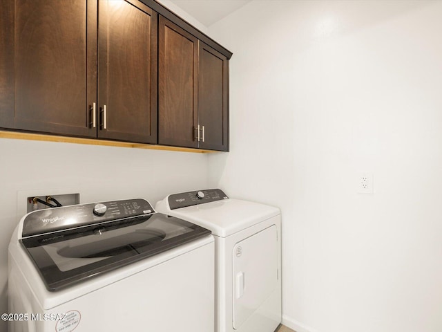 washroom with cabinet space, washing machine and dryer, and baseboards