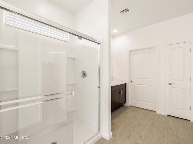 full bathroom featuring vanity, wood finished floors, a shower stall, and visible vents