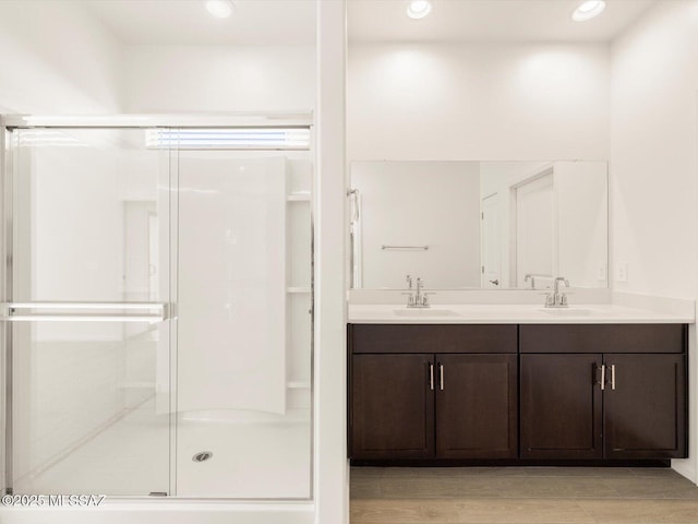 bathroom with double vanity, a shower stall, a sink, and recessed lighting
