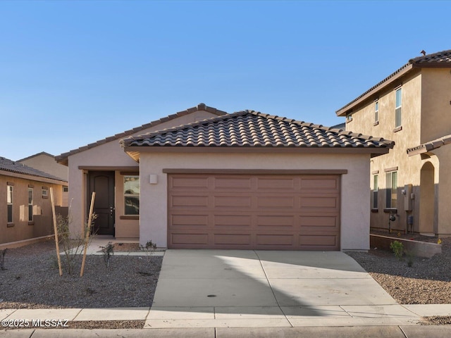 view of front of house featuring a garage, driveway, a tiled roof, and stucco siding