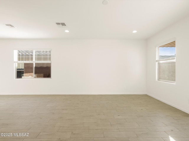empty room featuring recessed lighting, visible vents, light wood finished floors, and baseboards