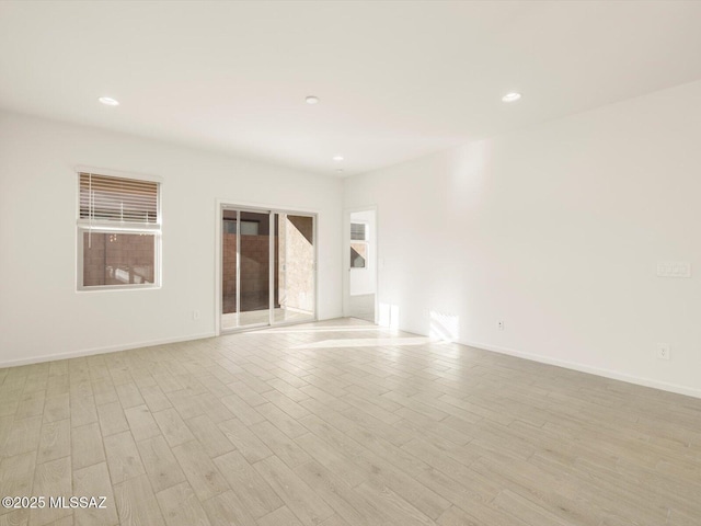 empty room with baseboards, recessed lighting, and light wood-style floors