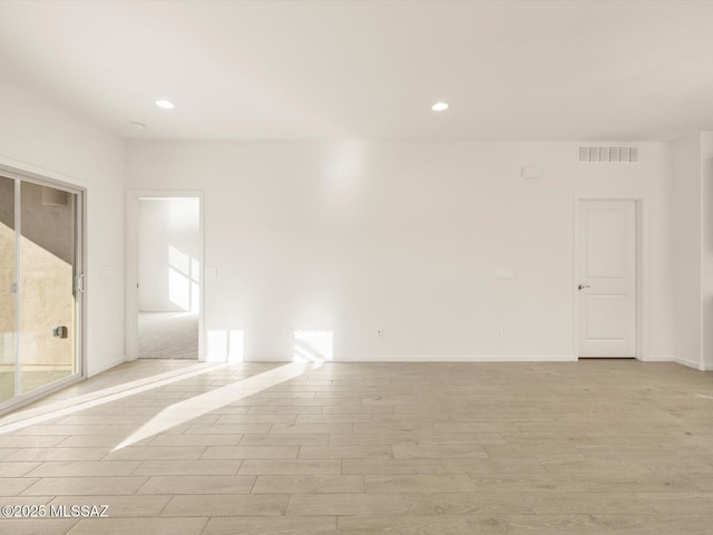 spare room featuring baseboards, light wood-type flooring, visible vents, and recessed lighting