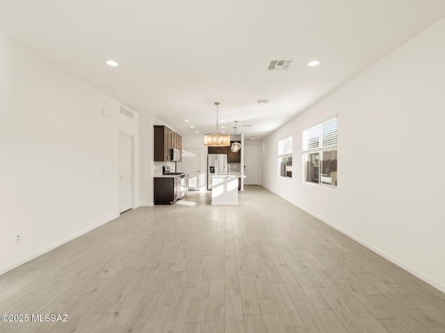 unfurnished living room featuring light wood-style flooring, visible vents, a notable chandelier, and recessed lighting