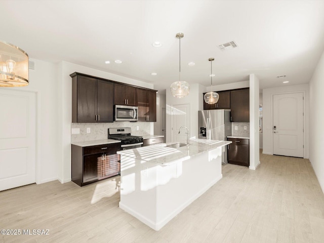 kitchen with stainless steel appliances, visible vents, a sink, and dark brown cabinets