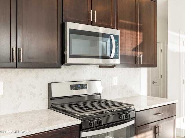 kitchen with dark brown cabinets, appliances with stainless steel finishes, backsplash, and light stone countertops