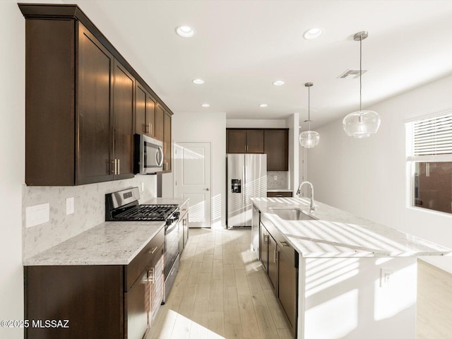 kitchen featuring visible vents, decorative backsplash, appliances with stainless steel finishes, a sink, and dark brown cabinets