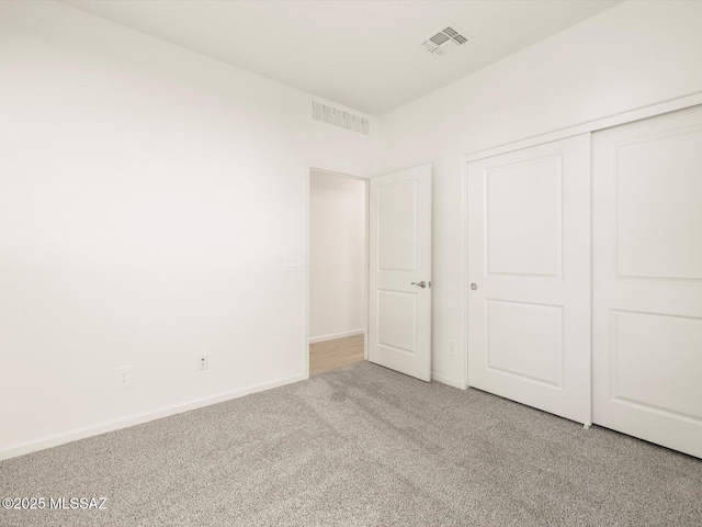 unfurnished bedroom with baseboards, a closet, visible vents, and carpet flooring
