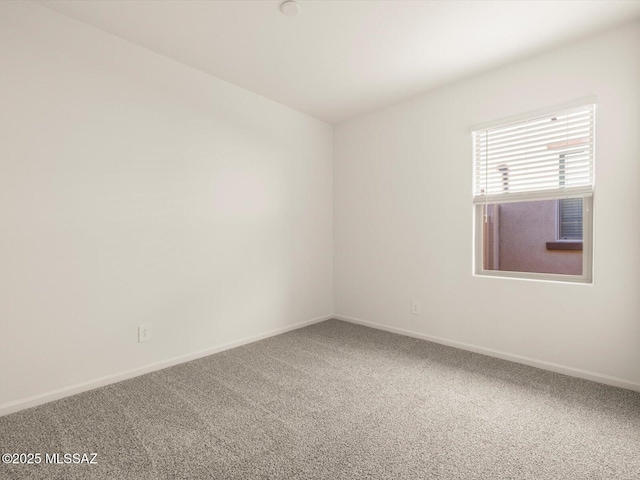 carpeted empty room featuring baseboards