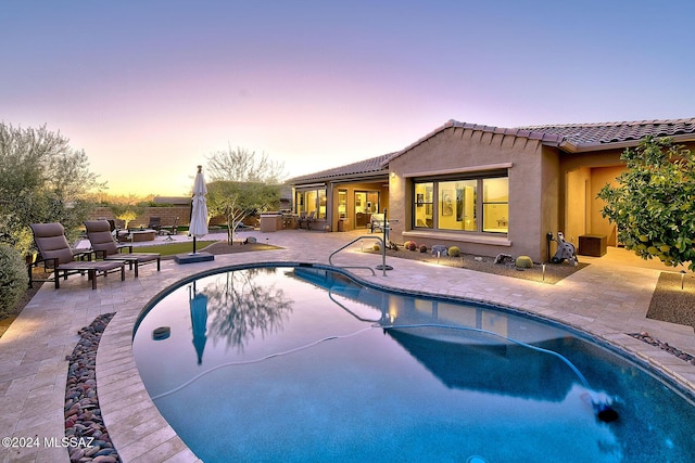 pool at dusk with a patio area