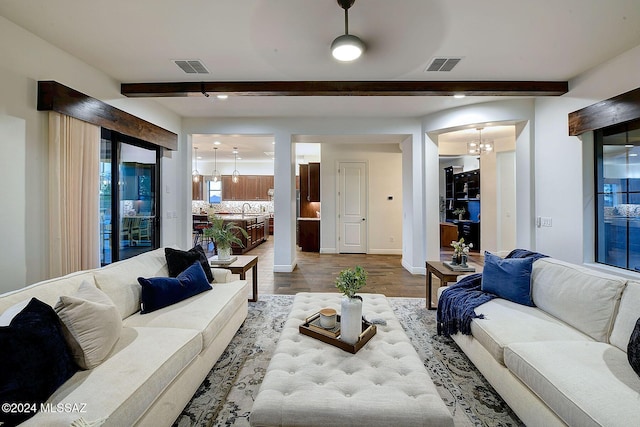 living room featuring hardwood / wood-style floors, beam ceiling, sink, and a chandelier