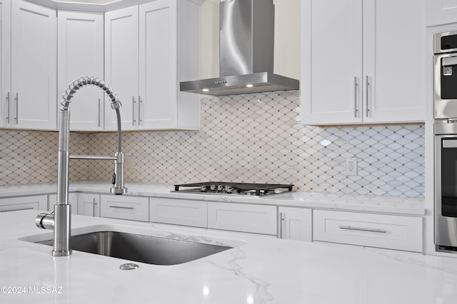 kitchen with white cabinets, wall chimney range hood, and stainless steel gas cooktop