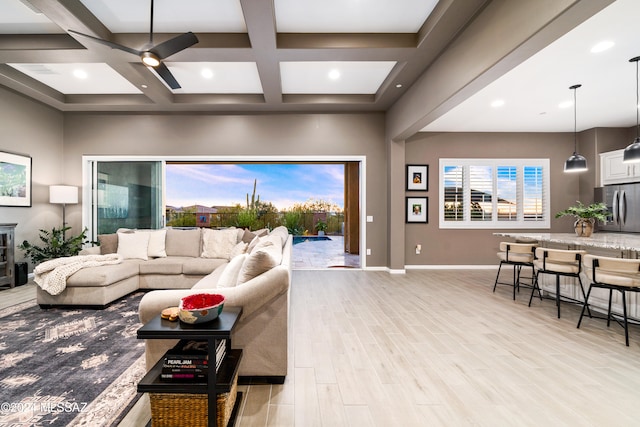 living room with ceiling fan, beam ceiling, light wood-type flooring, and coffered ceiling