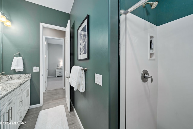 bathroom with hardwood / wood-style flooring, vanity, and a shower