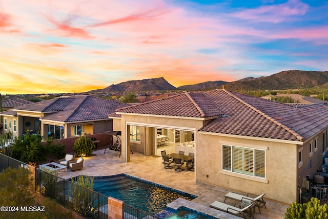 back house at dusk featuring a mountain view, a patio, and a fenced in pool