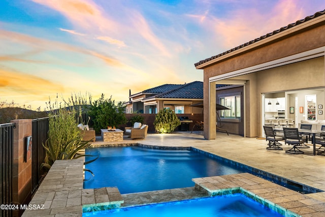 pool at dusk featuring pool water feature, a patio, grilling area, and a hot tub