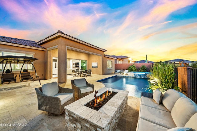 pool at dusk featuring a patio and an outdoor living space with a fire pit