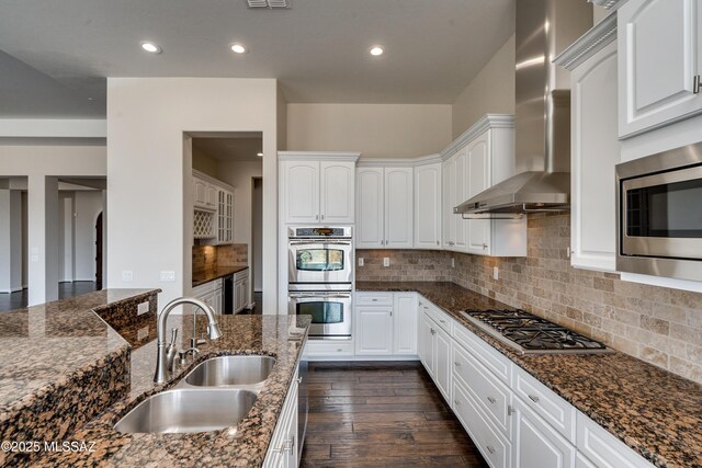 kitchen featuring appliances with stainless steel finishes, dark hardwood / wood-style flooring, wall chimney exhaust hood, a center island, and white cabinetry