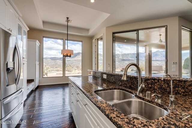 kitchen featuring wall chimney exhaust hood, dark wood-type flooring, stainless steel appliances, decorative light fixtures, and stone countertops