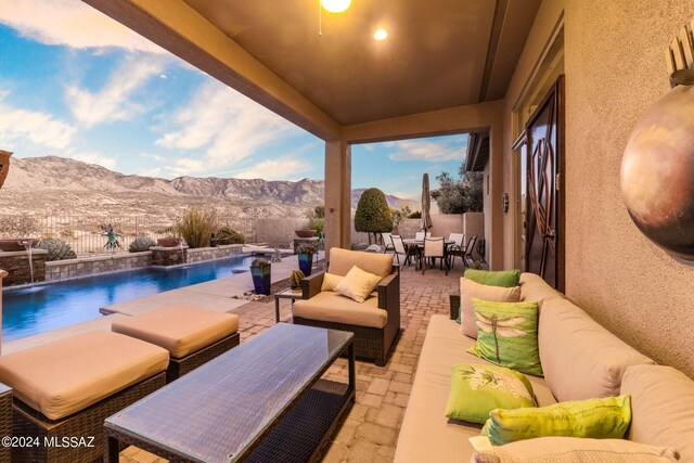 pool at dusk with outdoor lounge area and a patio