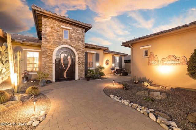 exterior entry at dusk with a patio area