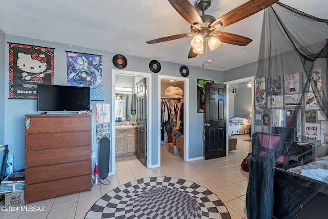 tiled bedroom featuring connected bathroom, a spacious closet, a closet, and ceiling fan