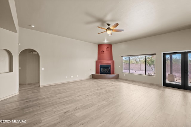 unfurnished living room with ceiling fan, light wood-type flooring, and a fireplace