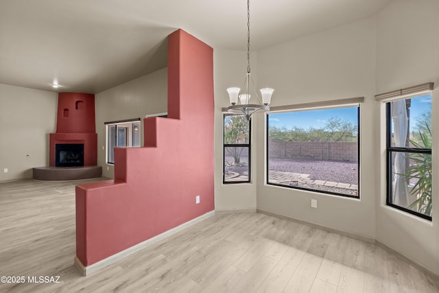 interior space featuring a fireplace, pendant lighting, light hardwood / wood-style floors, and an inviting chandelier