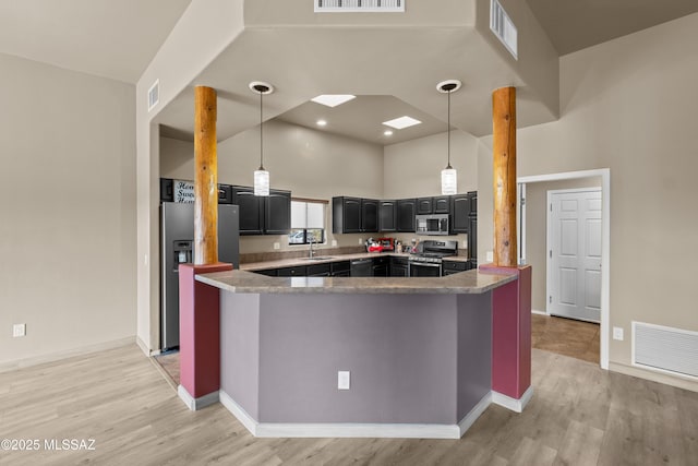 kitchen featuring sink, kitchen peninsula, stainless steel appliances, and a towering ceiling