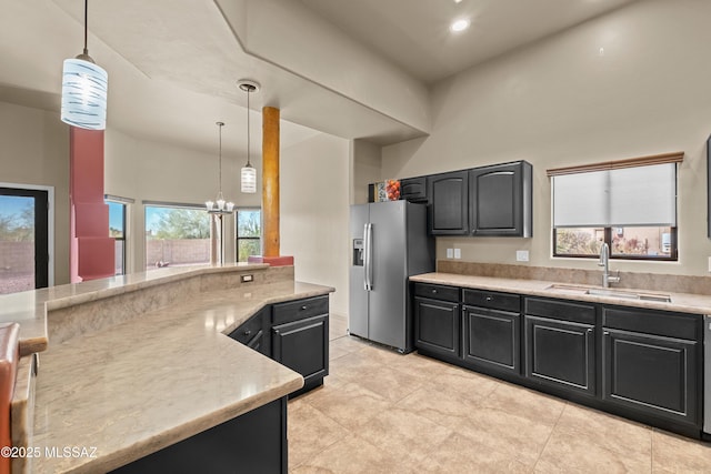 kitchen with stainless steel fridge, decorative light fixtures, a notable chandelier, and sink