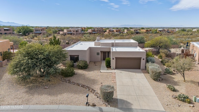 adobe home featuring a residential view, a garage, stucco siding, a mountain view, and driveway