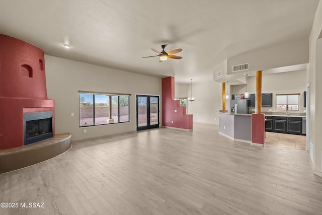 unfurnished living room featuring visible vents, baseboards, ceiling fan, light wood-type flooring, and a large fireplace
