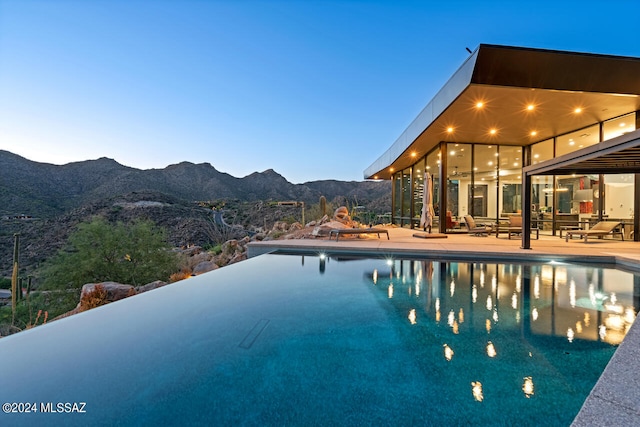 pool at dusk featuring a patio area and a mountain view