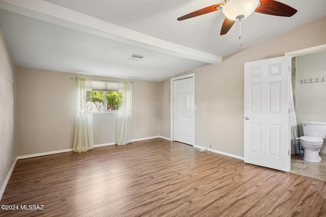 unfurnished bedroom with connected bathroom, ceiling fan, lofted ceiling with beams, and hardwood / wood-style flooring