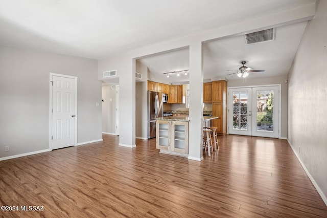 unfurnished living room with hardwood / wood-style flooring, ceiling fan, track lighting, and french doors