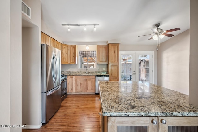 kitchen featuring sink, french doors, light stone counters, light hardwood / wood-style floors, and appliances with stainless steel finishes