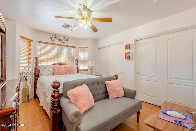 bedroom with multiple closets, ceiling fan, and light hardwood / wood-style floors