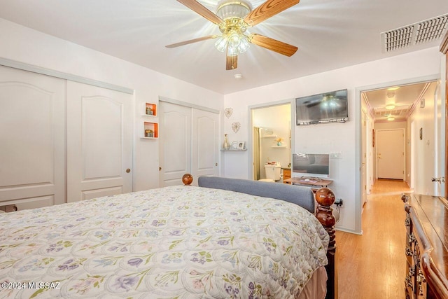 bedroom with ceiling fan, light wood-type flooring, and two closets