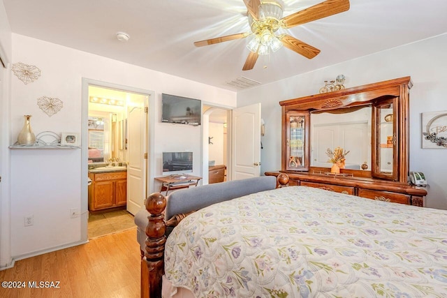 bedroom featuring ceiling fan, ensuite bath, and light hardwood / wood-style flooring